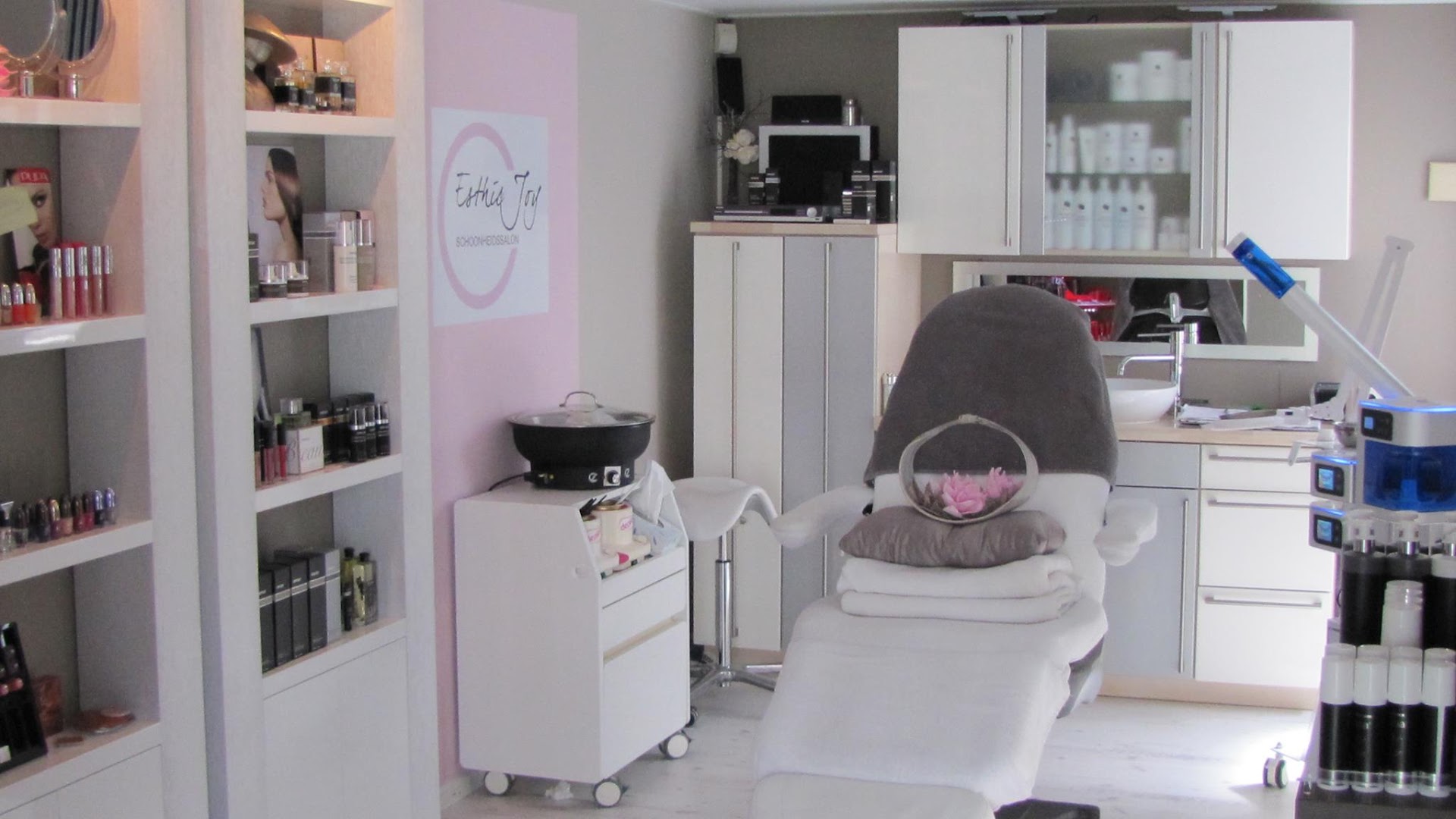 Interieur van schoonheidssalon Esthic Joy met behandelstoel en het logo aan de muur